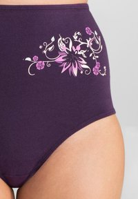 Mutande di cotone viola a vita alta con un design floreale in rosa e bianco, caratterizzate da intricate lavorazioni e una texture liscia.