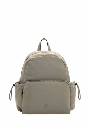 Mochila color beige con parte superior redondeada, dos compartimentos con cremallera, correas laterales ajustables y un logo en el bolsillo frontal. Tela texturizada.