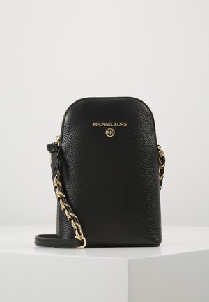 Sort tekstureret læder Michael Kors crossbody taske med guldkæde og logo foran, vist på hvid overflade mod lys baggrund.