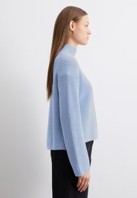 Hellblauer, gestrickter Pullover mit hohem Kragen, gerippter Textur und langen Ärmeln. Besitzt eine lockere Passform und ein weiches, gemütliches Material.