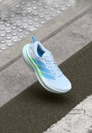 Scarpa sportiva azzurro chiaro con materiale in mesh, tre strisce blu e verde neon, suola imbottita e punta arrotondata.