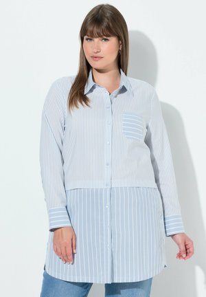 Blå och vit randig skjorta med knappslå, bröstficka och långa ärmar. Mjukt tyg och rundad nederkant.