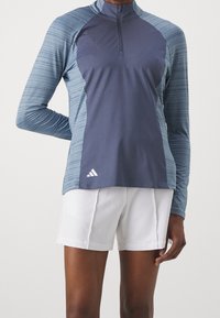 Long-sleeve athletic shirt in dark navy and light blue with a half-zip collar; features textured stripes and a white logo accent.