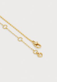 Colar de corrente de ouro com círculos entrelaçados e um pingente em forma de coração com uma pedra preciosa. Textura suave e acabamento polido. Fecho de clavícula.