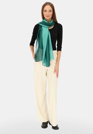 Prostokątny szal w kolorze morskim, wykonany z lekkiego materiału, ułożony elegancko. Modelka ma na sobie czarną bluzkę i kremowe spodnie o szerokich nogawkach, z błyszczącymi akcentami.