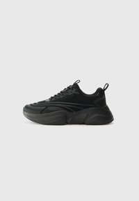 Black athletic shoes with a rounded sole, textured upper, and padded collar. Features lacing, a pull tab, and layered design elements.
