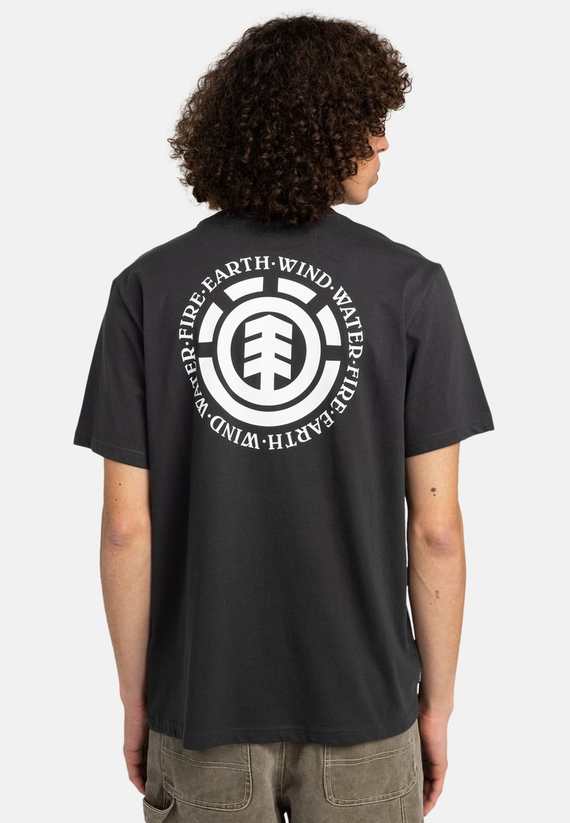 Zwarte katoenen t-shirt met een grote ronde witte grafiek op de achterkant met symbolen voor aarde, lucht, water en vuur. Korte mouwen.
