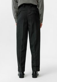 Zwarte broek met krijtstreep en een recht model, met een opgerolde zoom en riemlussen, gemaakt van een gestructureerde stof.