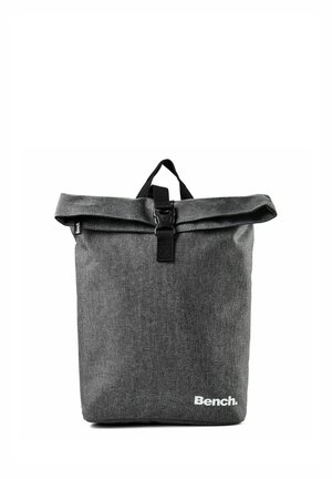 Dunkelgrauer Rolltop-Rucksack aus Stoff mit schwarzer Schnalle und Griff, mit dem weißen Schriftzug "Bench." unten rechts.