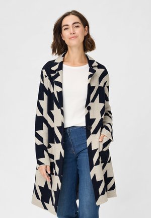 Strickmantel in Beige und Marineblau mit einem auffälligen Zickzackmuster, langen Ärmeln, einem kragenförmigen Ausschnitt und zwei aufgesetzten Taschen vorn.