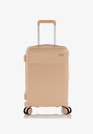 Hard-shell suitcase in pastel pink with ribbed texture, retractable handle, and four multi-directional wheels for easy mobility.