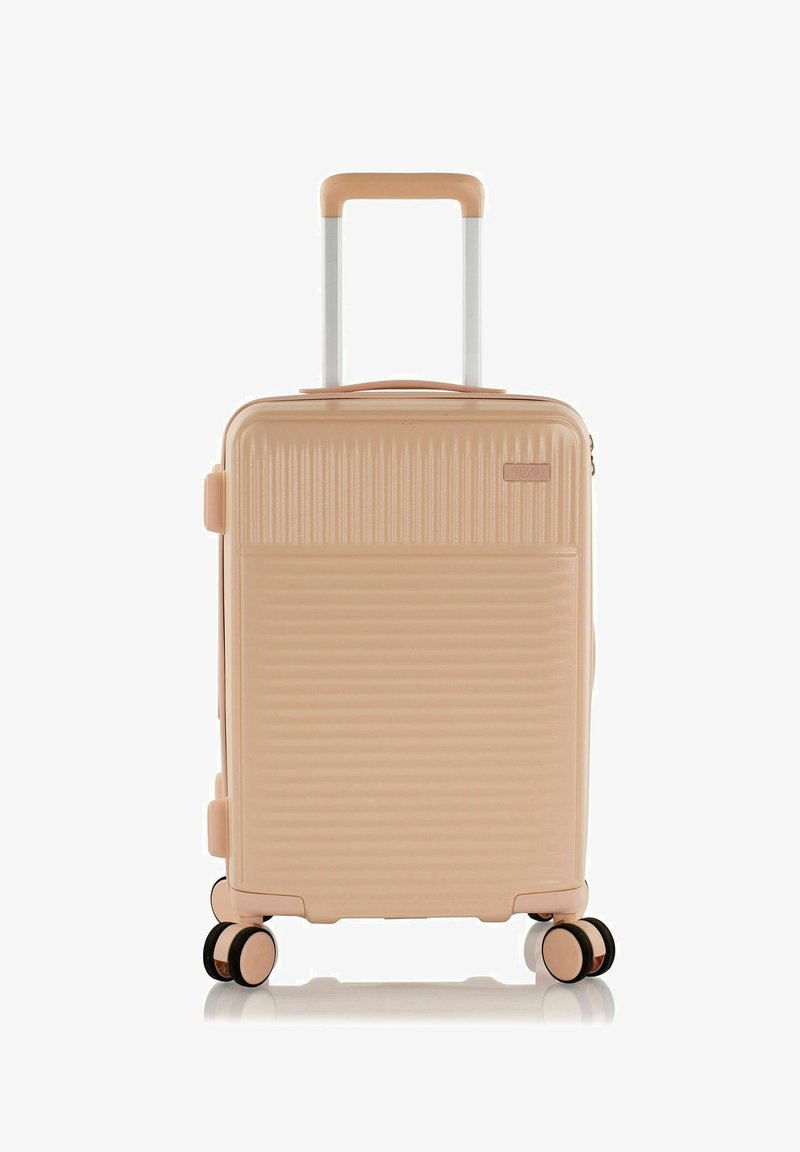 Valise rigide en rose pastel avec texture striée, poignée rétractable et quatre roues multidirectionnelles pour une mobilité facile.