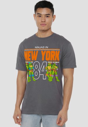 Gray cotton T-shirt featuring a graphic print of four turtles, with "NINJAS IN NEW YORK 84" in orange and white lettering.