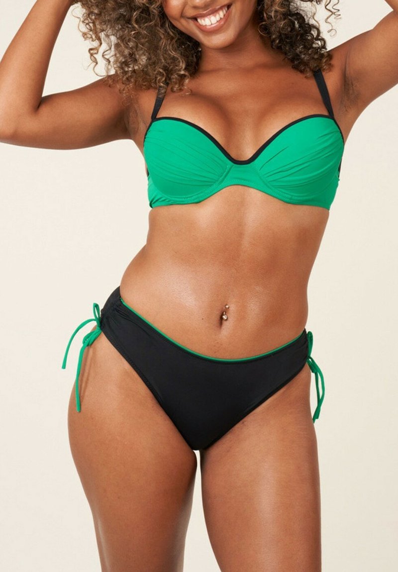 Ensemble de bikini comprenant un haut rembourré vert avec des accents noirs et un bas noir avec des bordures vertes et des liens sur les côtés, fabriqué en tissu de maillot de bain lisse.