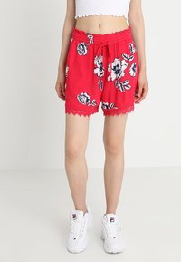 Rode bloemenkorte broek gemaakt van lichte stof, met een kanten rand aan de zoom en een elastische tailleband met een trekkoord.