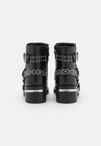Bottes en cuir noir à la cheville avec une tige mi-haute, des accents de boucles en argent, des clous décoratifs et un talon épais.