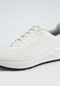Leichter Laufschuh in Weiß und Grau, mit einem Obermaterial aus Mesh, strukturiertem Design, Schnürsenkeln und einer gepolsterten Sohle mit schwarzem Gummiprofil.