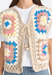 Crocheted vest features a beige base with multicolored circular patterns in pink, blue, yellow, and white. Textured with soft yarn and fluffy accents.