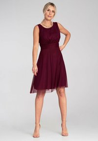 Bordeauxfarbenes Kleid mit gefaltetem Oberteil, taillierter Taille und schwingendem Rock, hergestellt aus leichtem Stoff. Wird mit ärmellosem Design und transparenter Overlay geliefert.