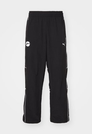 Melnas sporta bikses ar brīvu pieguvi, elastīgu jostu, baltām sānu maliņām un logo detaļu kreisajā augšstilbā. Viegls audums.
