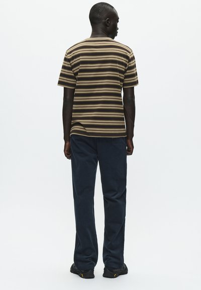 T-shirt a righe a maniche corte marrone e beige, abbinato a pantaloni blu scuro. Il tessuto appare morbido; la vestibilità è rilassata e informale.