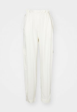 Cremfarbene Hose mit Kordelzugbund, seitlichen Taschen und lockerer Passform. Hergestellt aus einem weichen Stoff mit glatter Textur.
