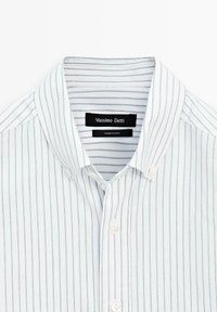 Biała koszula w paski z niebieskimi liniami, z kołnierzykiem zapinanym na guziki i białymi guzikami. Metka informuje "Massimo Dutti". Materiał bawełniany, gładka faktura.
