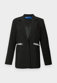 Μαύρο σακάκι με ραμμένο κόψιμο, κλείσιμο με ένα κουμπί, δύο μπροστινές τσέπες και τονίζεται με λογότυπα "Karl" στα πλάγια. Απαλή υφή υφάσματος.