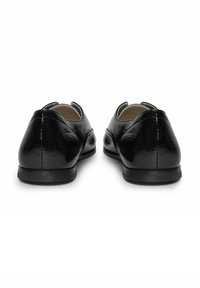 Zwarte gepatineerde leren schoenen met een afgeronde neus, een gladde textuur, lage hak en zonder decoratieve accenten, gezien vanuit de achterkant.