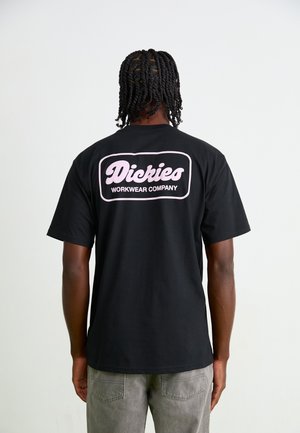 Black cotton T-shirt featuring a pink graphic on the back with the text "Dickies WORKWEAR COMPANY." Short sleeves and relaxed fit.