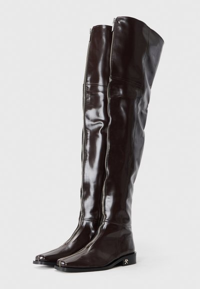 Hohe, glänzende braune Leder-Stiefel über dem Knie mit seitlichen Reißverschlüssen, quadratischen Zehen und flachem schwarzem Absatz mit einem metallischen Akzent.