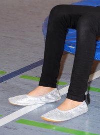 Zilveren glitter ballerina's met ronde neuzen en een flexibele zool, gedragen met zwarte leggings op een gymvloer.