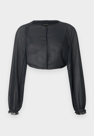Blouse noire transparente à manches longues cropped avec poignets élastiqués et col rond sur un fond clair.
