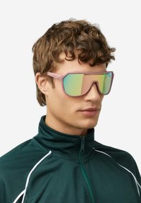 Očala za sonce z rožnatim okvirjem in velikimi, odsevnimi, gradientnimi lečami. Oblika vključuje ostre kote in športno estetiko.