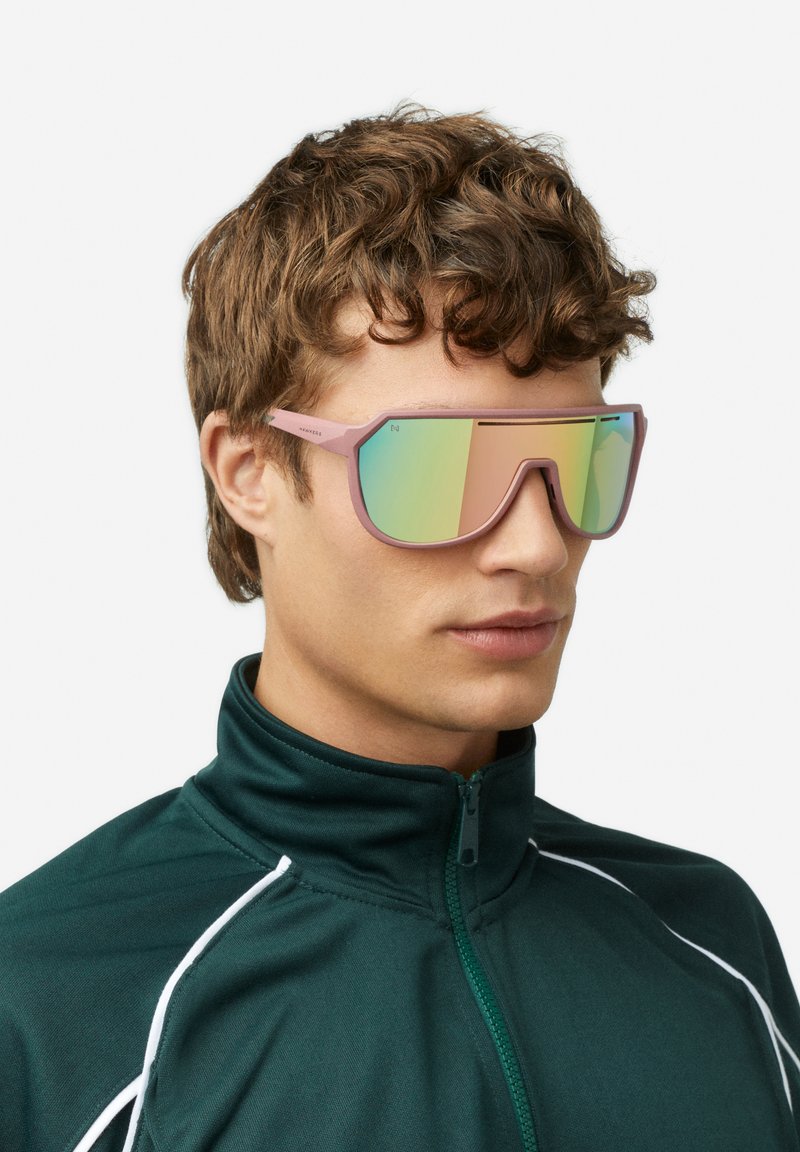 Očala za sonce z rožnatim okvirjem in velikimi, odsevnimi, gradientnimi lečami. Oblika vključuje ostre kote in športno estetiko.