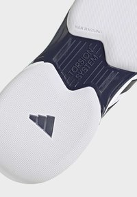 White athletic shoe sole featuring a textured surface, dark blue Torsion System accent, and non-marking rubber with triangular logo detail.