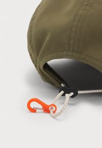 Olive green cap with a textured fabric, featuring an adjustable strap with an orange carabiner and white cord. Rounded peak, stitched seams.