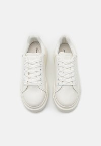 Hvide sneakers med en glat læderoverdel, rund tå, flade snørebånd, polstret krave og struktureret gummisål. Brandnavn trykt indvendigt.