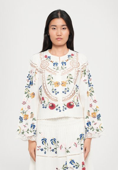 Bestickte Bluse mit floralen Mustern in Rot, Blau und Gelb. Hergestellt aus weißem Stoff mit Spitzelementen und mit rundem Ausschnitt.