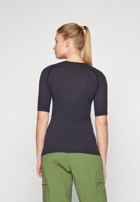 Form-fitting, short-sleeved top in dark navy, featuring textured fabric and subtle patterns, paired with olive green cargo pants.