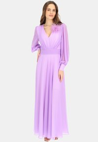 Długa lawendowa sukienka z zwiewnego materiału. Posiada głęboki dekolt w kształcie litery V, plisowany gorset i bufiasty rękawy. Zauważalny puszysty akcent na ramieniu.