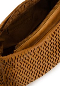Tan leather bag with perforated texture. Features a zip closure and a lined interior. Label visible inside, reading "Venezia."