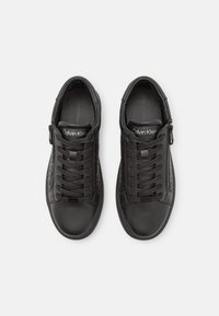 Zapatillas de cuero negro con un acabado suave, que cuentan con acentos laterales texturizados, cordones en la parte delantera y un cierre con cremallera para mayor comodidad.