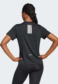 Sort svedtransporterende atletisk t-shirt med korte ærmer, der har tre hvide lodrette striber på ryggen og "LES MILLS" logo på kanten.