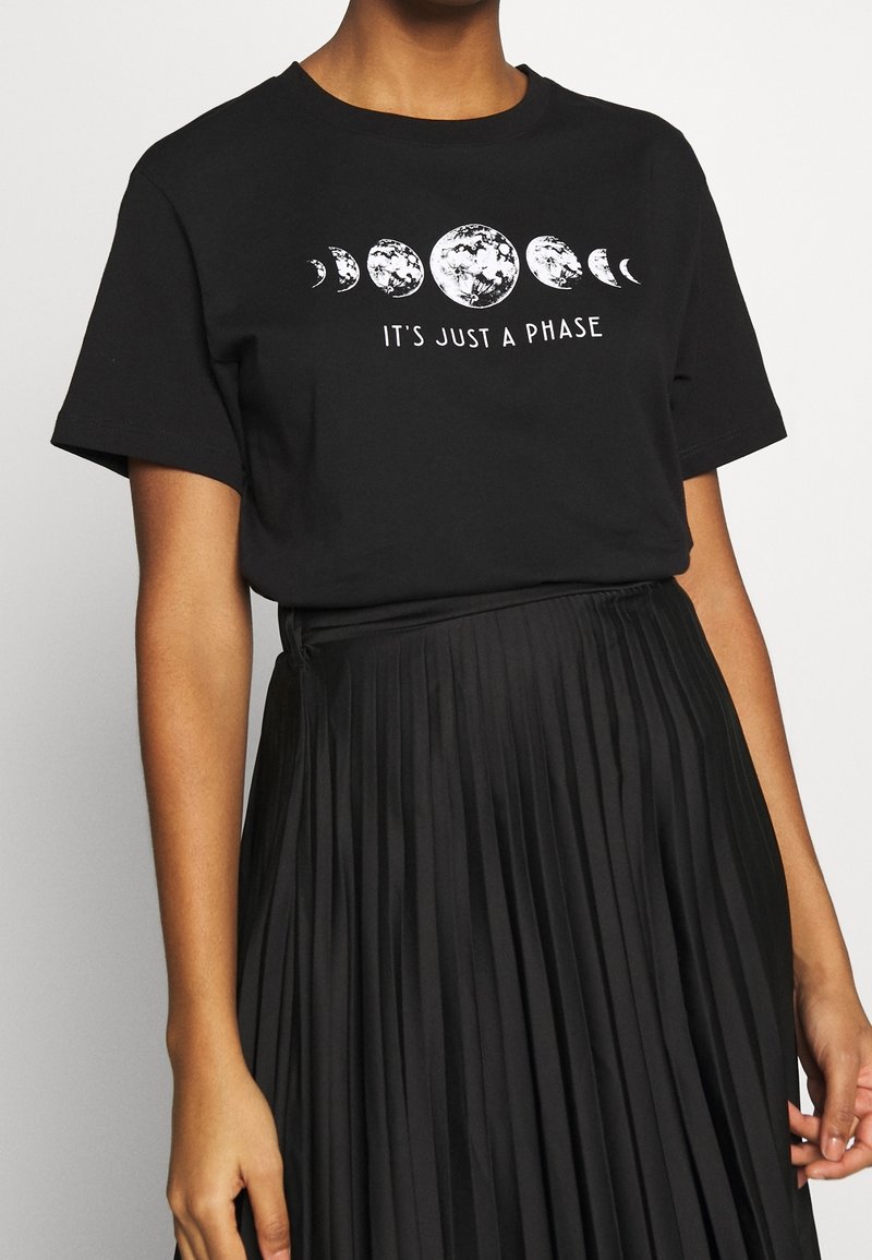 Svart bomulls T-shirt med vit grafik av månens faser och texten "DET ÄR BARA EN FAS." Korta ärmar, avslappnad passform.