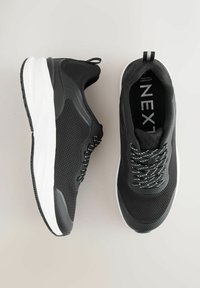 Mustad spordijalatsid hingava võrgust ülaosaga, valge keskmise tallaga ja mustriliste kinnistega. Omavad tekstuuriga varbakatet ja konksutõmbe linti.