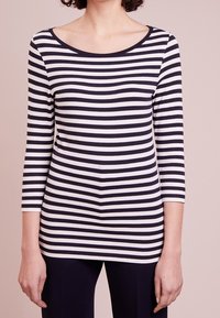 Pitkät hiharatkaisut tummansinisissä ja valkoisissa raidoissa. Ominaisuuksina laaja pääntie ja pehmeä, kevyt materiaali, jossa on vartalonmyötäinen malli.