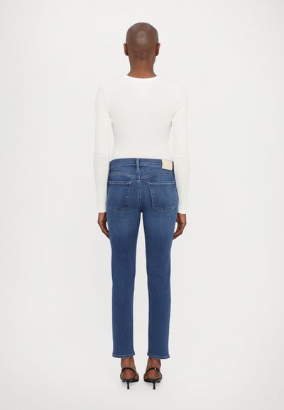 Donkerblauwe denim jeans met een slim fit en rechte pijpen. Voorzien van twee achterzakken en een lichtgekleurde label bij de tailleband.