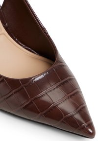 Pump marrone a punta con un motivo in pelle di coccodrillo testurizzata e un interno beige liscio. Presenta una silhouette elegante e lati profondi.