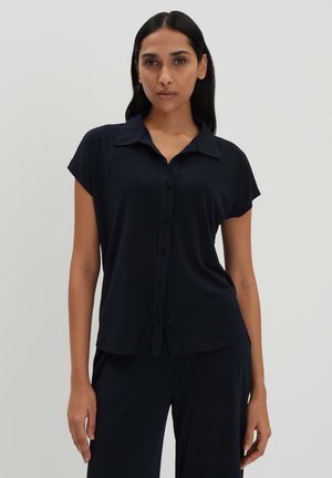 Camicia a maniche corte blu navy in tessuto morbido con colletto a punta e orlo ben ripiegato. Bottoni frontali e vestibilità comoda.